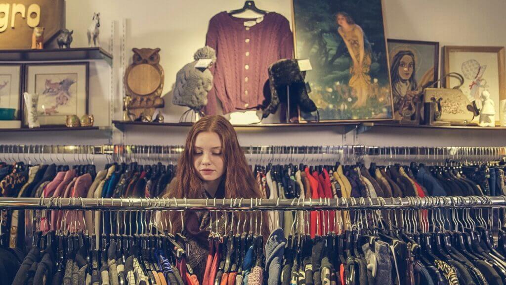 young woman looks at clothing at resale shop